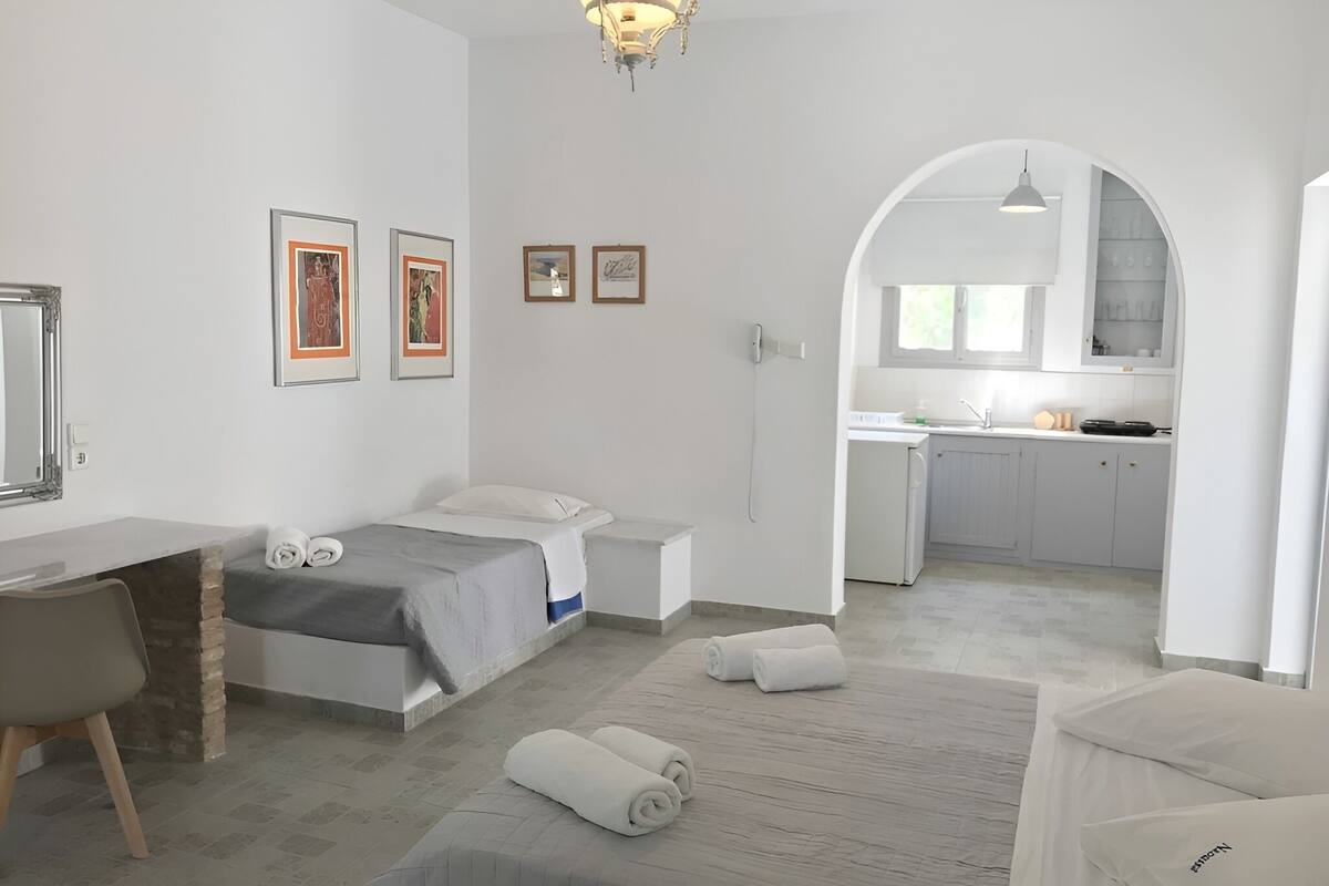 Una habitación de hotel moderna con cama, escritorio, silla y kitchenette.