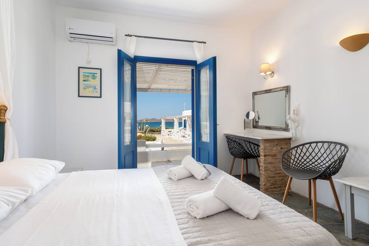 Habitación de hotel con cama, escritorio, silla y vista a la playa.