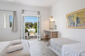 A bedroom with two beds, a desk, and a chair. - Naoussa Hotel (Paros)