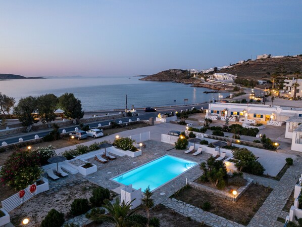 A resort with a swimming pool, lounge chairs, and a view of the sea.