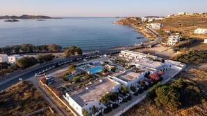 An aerial view of a coastal area with buildings, a swimming pool, and a road. - Naoussa Hotel (Paros)