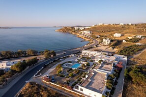 A coastal property with a swimming pool, a road, and buildings. - Naoussa Hotel (Paros)