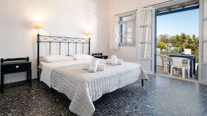 A hotel room with a bed, two bedside tables, a desk, and a view of the outdoors. - Naoussa Hotel (Paros)