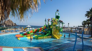 Ein Wasserpark mit Rutschen und Poolbereich, umgeben von Palmen und Liegestühlen.