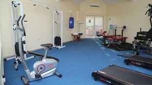 Ein Fitnessstudio mit Laufbändern, Kraftbänken und einem Sandsack.