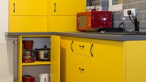 A kitchen with yellow cabinets, a red microwave, a coffee maker, and a toaster. - Redbed Self-catering Apartments (Bucharest)