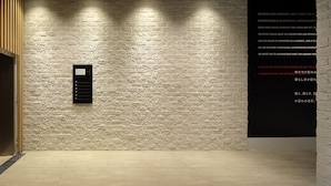 An elevator with a digital display and a wall with a textured pattern. - H Daimyo (Fukuoka)