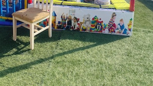 A play area with a fenced enclosure, a slide, and a seating area with a chair and a table. - Furnished chalet for rent, suitable for 5 people (South Sinai Governorate)