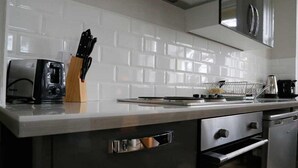 A kitchen with white subway tiles, a toaster, a knife block, and a coffee maker. - Coldeast Mansion (Southampton)