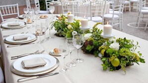 A table set for a formal outdoor dining event with white tablecloths, silverware, and candles. - Coldeast Mansion (Southampton)