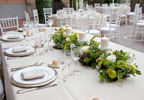 A table set for a formal outdoor dining event with white tablecloths, silverware, and candles. - Coldeast Mansion (Southampton)