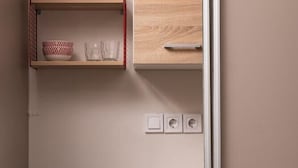 A kitchen with a stainless steel refrigerator, wooden cabinets, and a red wire shelf holding cups and glasses. - Xenofontos Inn by Livin Urbban (Athens)