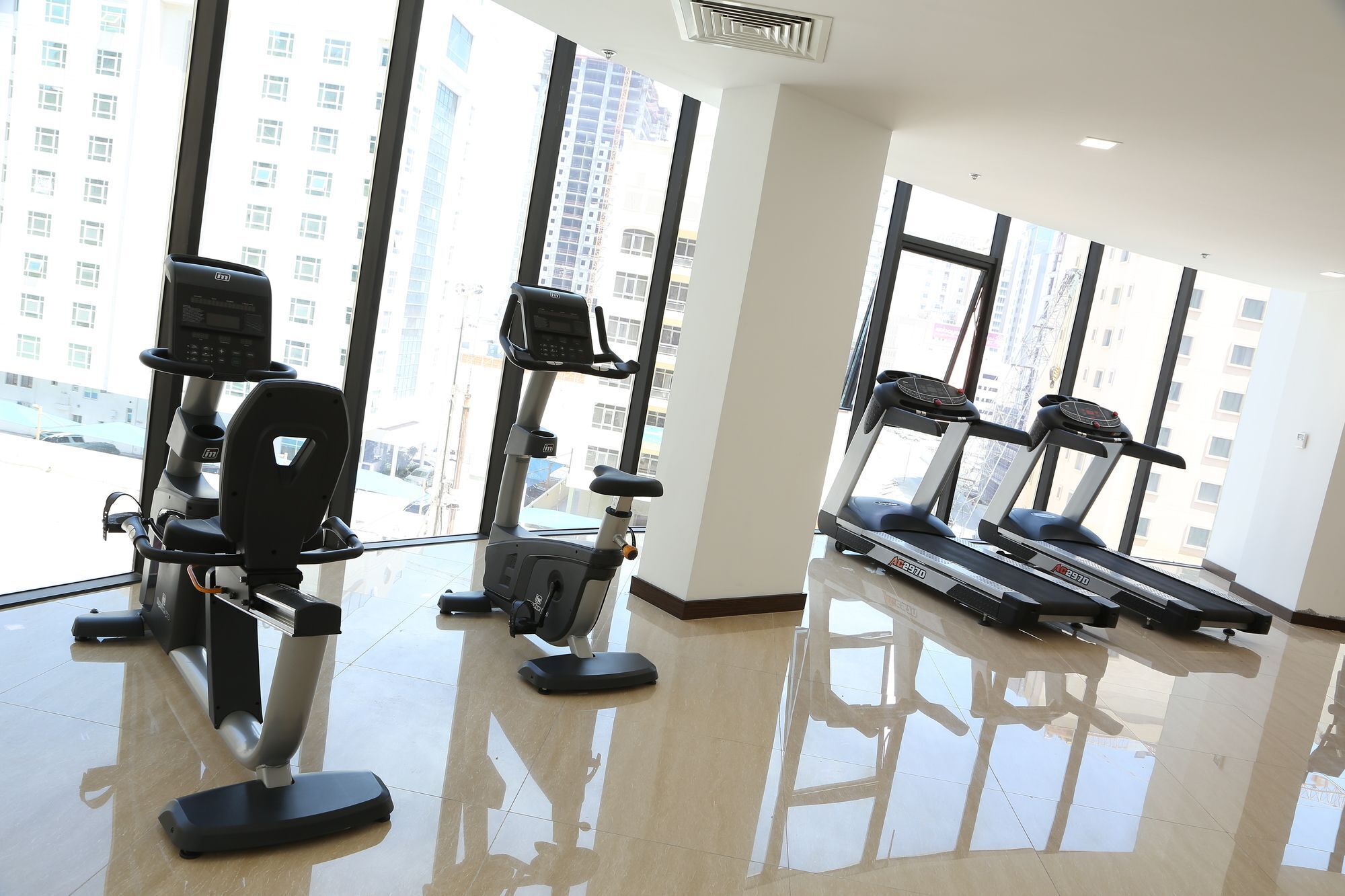 A gym with treadmills, elliptical machines, and a mirrored floor.
