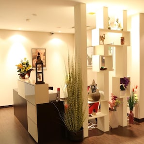 A reception desk with a framed artwork, a potted plant, and a small statue. - Belle Tower Luxury Hotel Apartments (Manama)