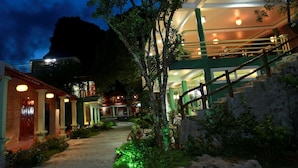 A hotel with a staircase leading to a balcony, surrounded by greenery and a mountain backdrop. - Trang An Eco Homestay Ninh Binh (Hoa Lu)