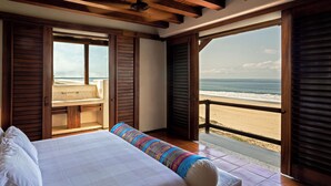 Un dormitorio con una cama grande, persianas de madera y vista a la playa.