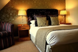 A hotel room with a bed, two nightstands, a striped armchair, and floral wallpaper. - THE Bridge Hotel AND SPA (Wetherby)