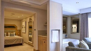 A hotel room with a bed, a bathroom with a bathtub, a sofa, and a mirror. - The Fairlawns Hotel And Spa (Walsall)