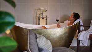 A bathtub with a vintage design, a glass of red wine, and a towel on a chair. - THE Fairlawns Hotel AND SPA (Walsall)