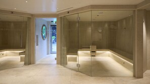 Moderni spa-huone, jossa on lasiseinät, puulattia ja näkyvissä oleva puutarha ulkona.