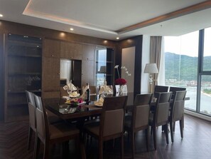 A dining area with a large table, chairs, and a view of a body of water. - Alansea Danang Hotel (Da Nang)