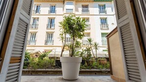 A potted plant on a balcony with a view of a building with multiple windows and balconies. - Nice Home Studio (Nice)