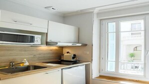 A compact kitchen with a microwave, sink, and a compact refrigerator. - Nice Home Studio (Nice)