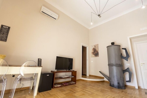 A living room with a TV on a wooden stand, a coffee table, and a large metal sculpture. - B&B City Soul Typical Resort (Naples)