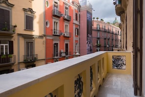 A narrow corridor with balconies, a marble ledge, and a yellow wall with a decorative metal railing. - B&B City Soul Typical Resort (Naples)