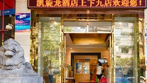 A hotel entrance with a large golden sign, a lion statue, and a staircase leading up to the door.