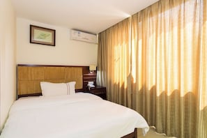 A hotel room with a large bed, a wooden headboard, a bedside table with a lamp, and a window with curtains. - Kaiserdom Hotel Shangxiajiu (Guangzhou)