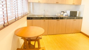 A compact kitchen with wooden cabinets, a black countertop, a stainless steel sink, and a microwave. - My Living Place Chaweng Beach (Koh Samui)