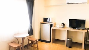 A compact hotel room with a kitchenette, a small dining table, a TV, and a window with curtains. - My Living Place Chaweng Beach (Koh Samui)