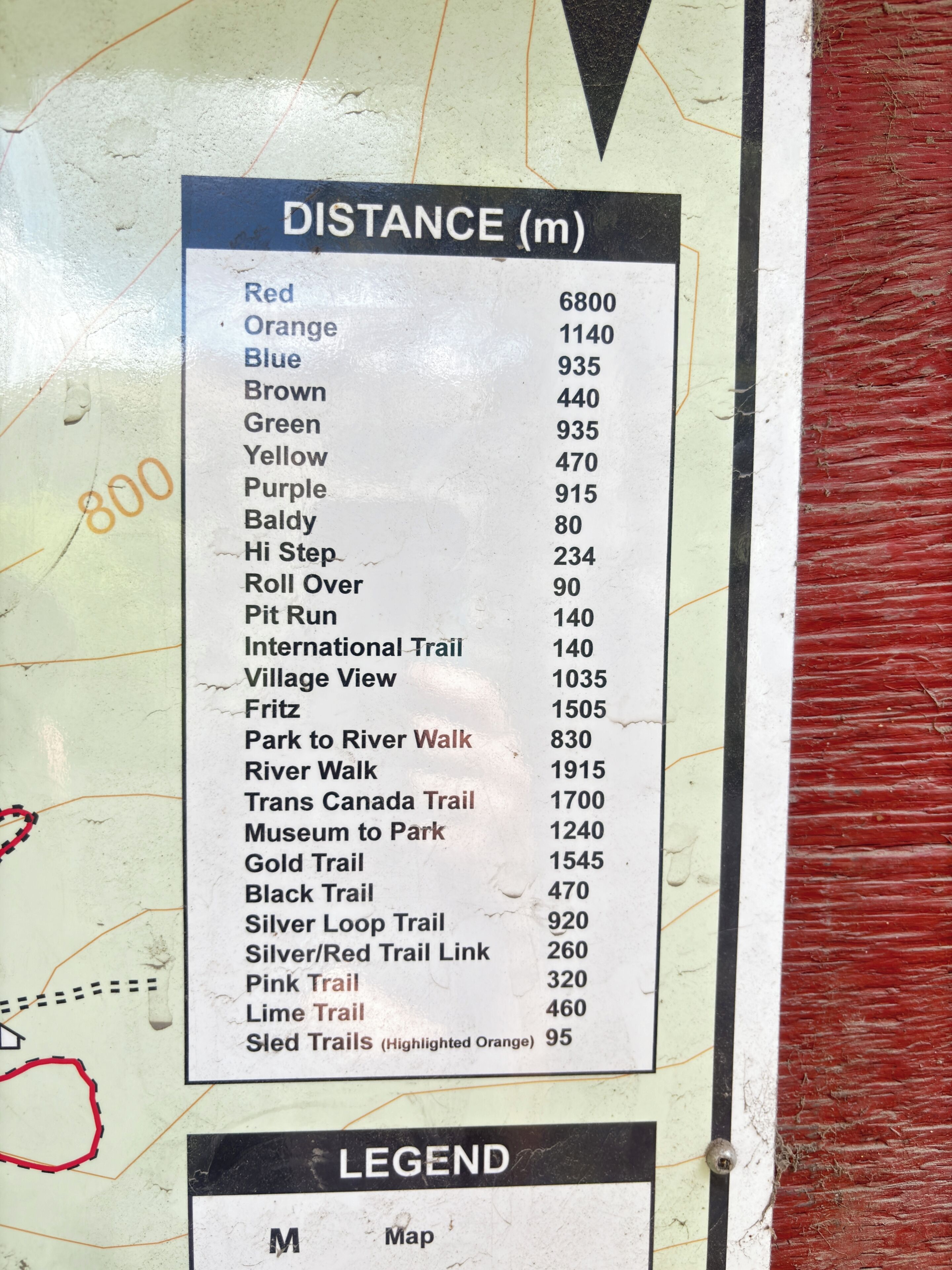 Un tableau indiquant les distances de différents sentiers et parcours de course, notamment les distances des sentiers rouge, orange et bleu.
