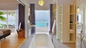 A modern hotel room with a large bathtub, a vanity with a mirror, and a view of the ocean. - Niva Kuramathi Maldives (Kuramathi Island)