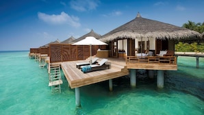 Overwater bungalows with thatched roofs, wooden decks, and lounge chairs. - Niva Kuramathi Maldives (Kuramathi Island)