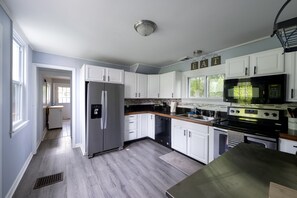 A modern kitchen with white cabinets, a stainless steel refrigerator, a black microwave, and a wooden countertop. - A Horse Racing Enthusiast's Delight / SPAC (Saratoga Springs)