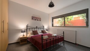 A bedroom with a bed, bedside tables, a window with a view, and a radiator. - Almond Villa (Rhodes)
