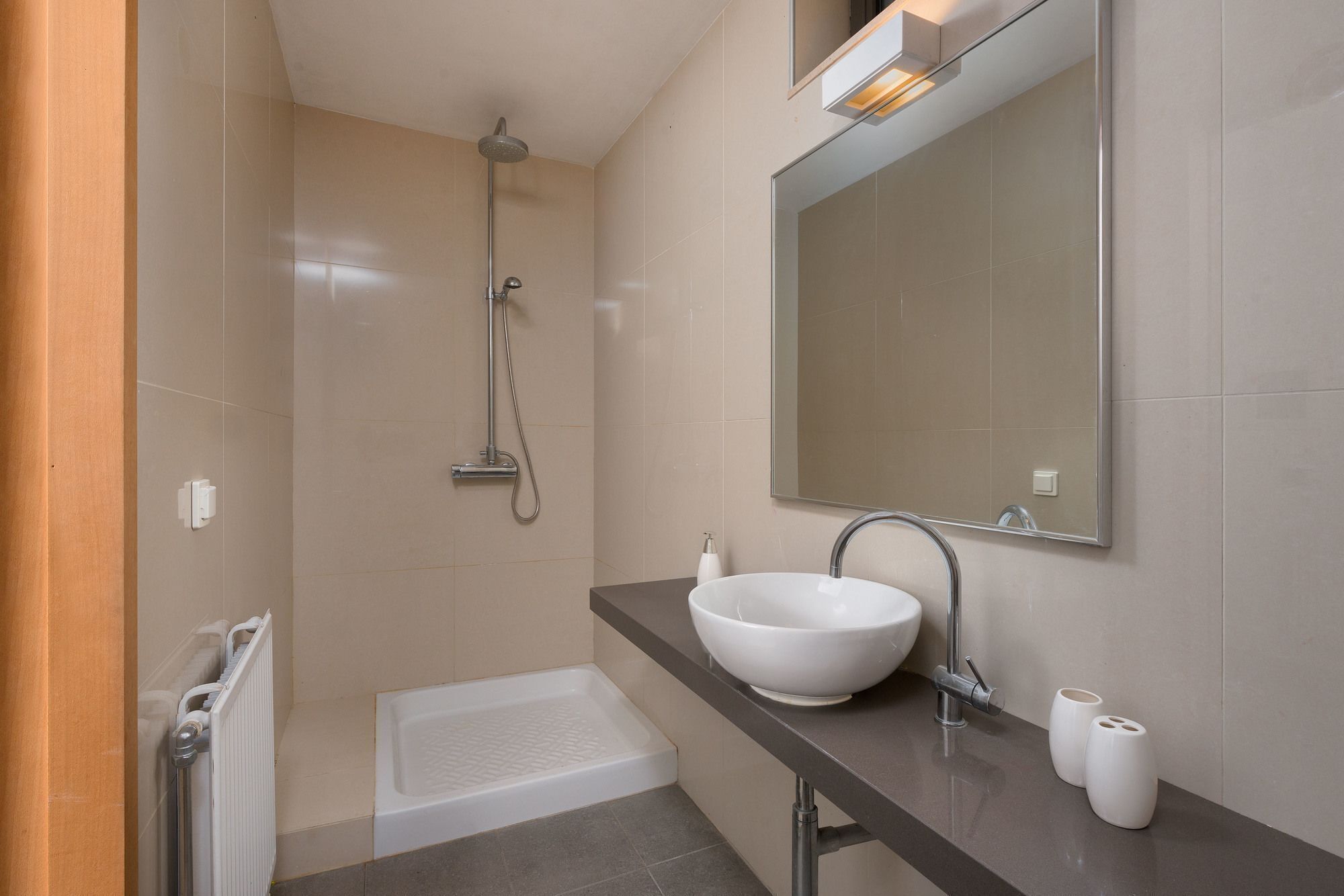 A modern bathroom with a white sink, a large mirror, a showerhead, and a bathtub.
