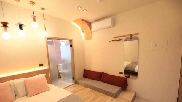 Ein Hotelzimmer mit Bett, Sitzgelegenheit, Spiegel und einer Tür zu einem Badezimmer.
