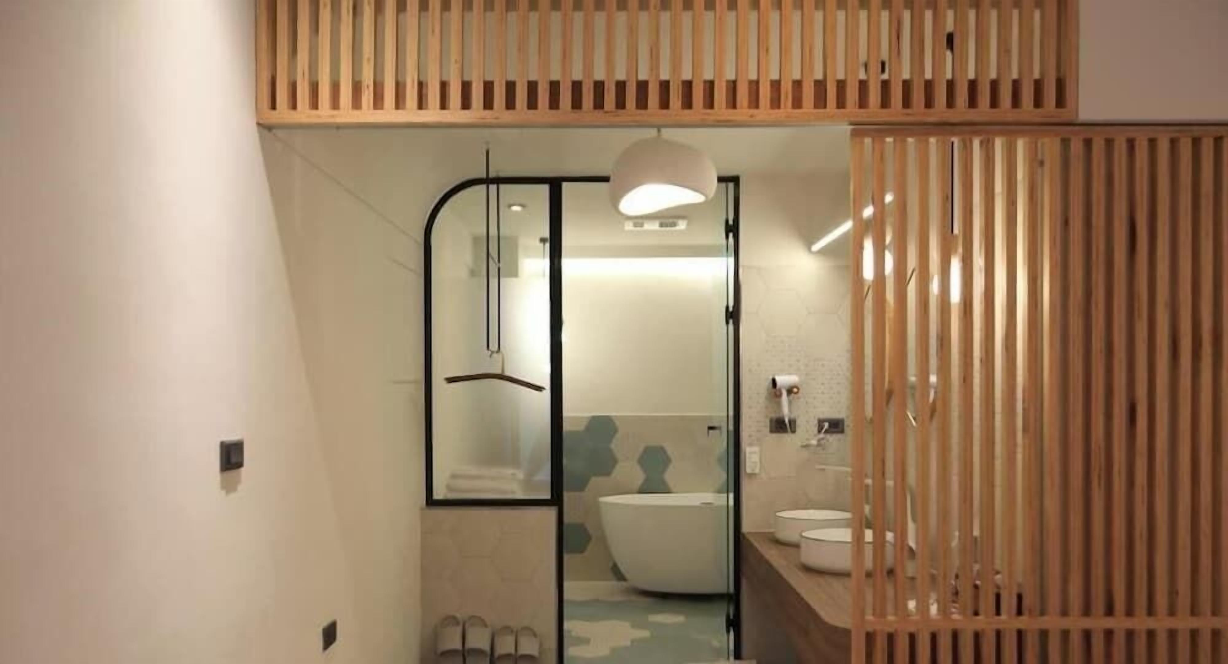 Een moderne badkamer met een glazen douchecabine, een ruime badkuip en een houten scheidingswand.