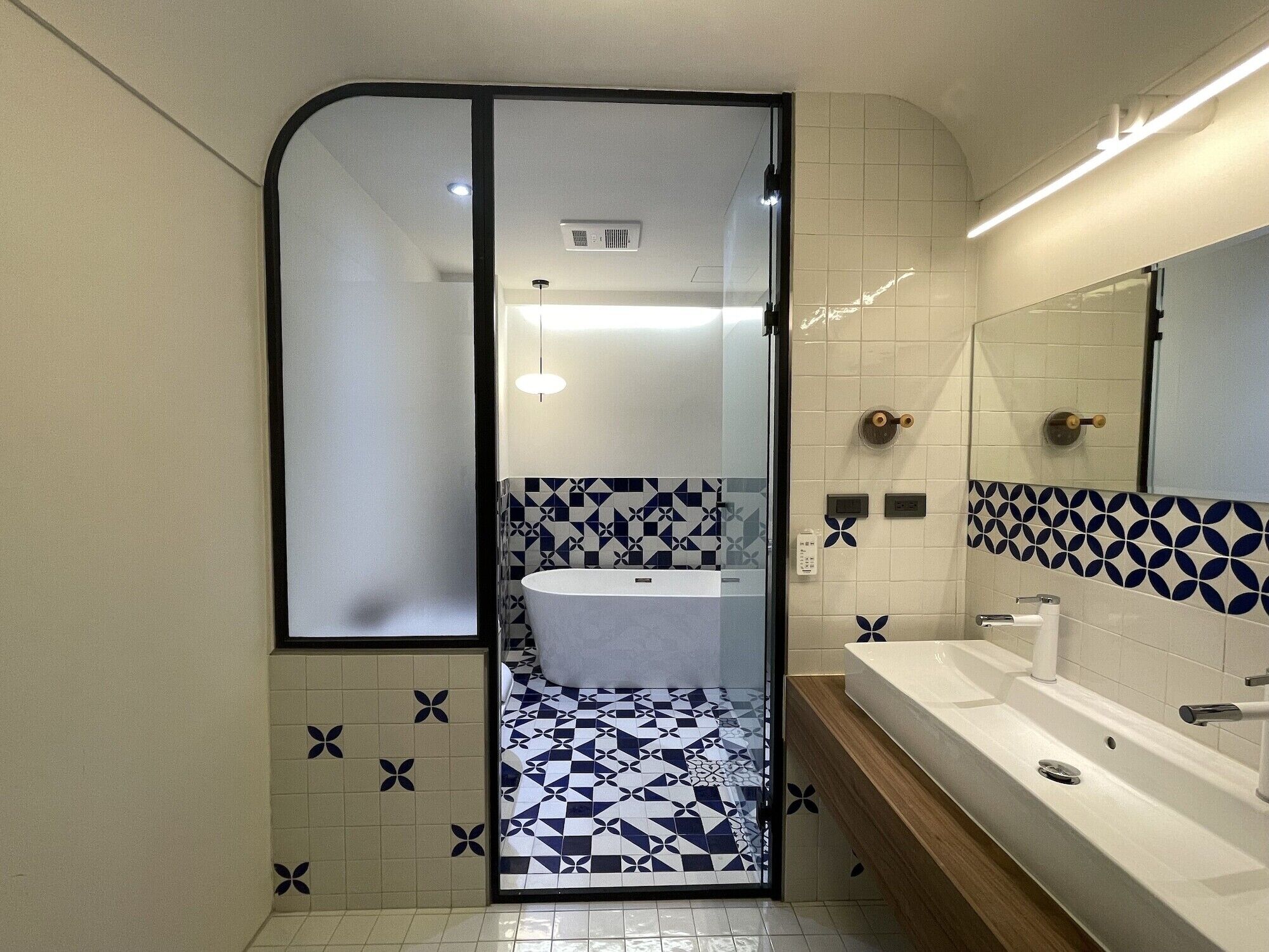 A modern bathroom with a glass partition, a sink, and a bathtub.