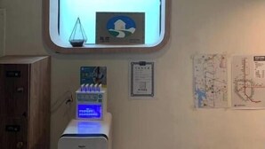 Ein Zimmer mit kleinem Fenster, einer wandmontierten Vorrichtung, einem Schrank und einigen Papieren an der Wand.