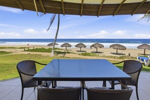 Un área de estar al aire libre cubierta con vista a la playa y al océano.