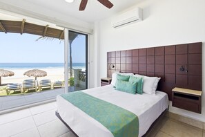 Un dormitorio con una cama grande, vista a la playa y ventilador de techo.