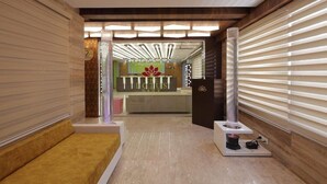 A reception area with a modern design, including a reception desk, seating area, and a decorative pillar. - Hotel The Lotus Park (Ahmedabad)