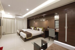 Une chambre d’hôtel avec deux lits, un bureau, une chaise, une table basse en verre et une armoire.