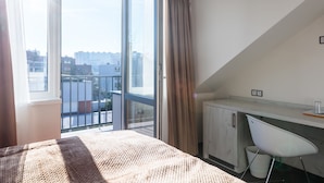 A bedroom with a large window, a bed, a desk, and a chair. - Hotel Shato (Prague)