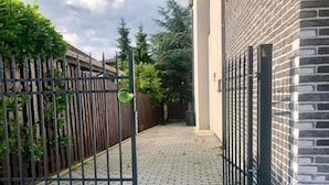 A gated entrance with a brick pathway leading to a building with a brick facade. - Hotel Shato (Prague)