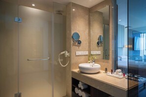 A modern bathroom with a glass shower enclosure, a white sink, and a large mirror. - Renaissance Ahmedabad Hotel (Ahmedabad)